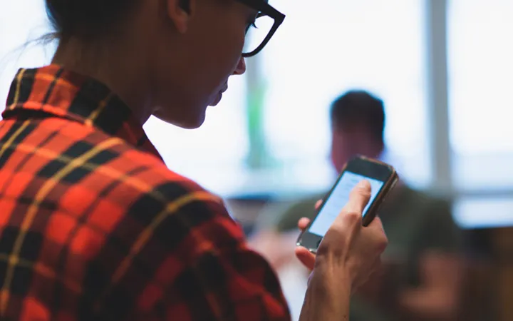 Kvinna håller i en mobiltelefon.