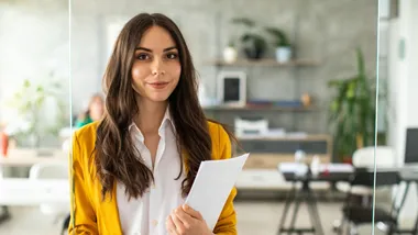 En kvinna som håller i dokument i en ljus kontorsmiljö